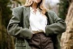 woman in gray and white polka dot blazer standing and smiling