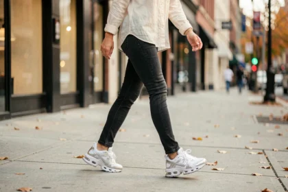 Femme portant des Nike Shox blanches marchant sur un trottoir urbain en automne, illustrant le confort au quotidien
